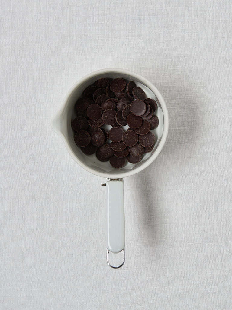 Dunkle Schokodrops in weißer Schüssel – Zutat für Protein Pistazieneis Topping