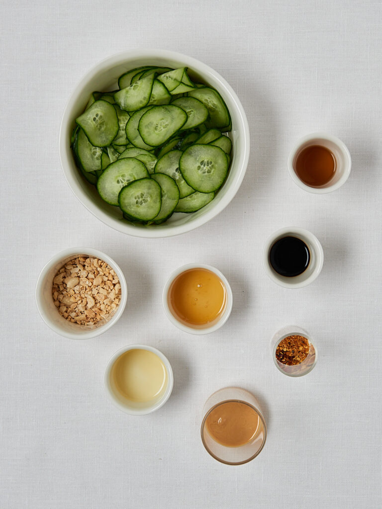 Zutaten-Flatlay Gurken Erdnuss Salat – Gurkenscheiben, Sojasauce, Sesamöl und Erdnüsse