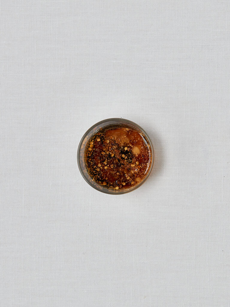 Erdnuss-Sojasauce Dressing mit Chiliflocken in Schüssel – Zubereitungsschritt
