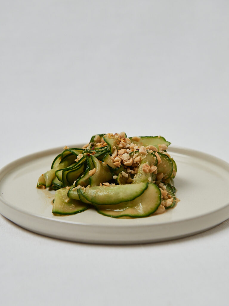 Gurken Erdnuss Salat mit cremigem Erdnuss-Dressing auf rundem Teller – seitliche Aufnahme