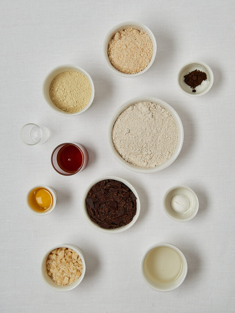 Zutaten-Flatlay Macadamia Cookies – Hafermehl, Proteinpulver, Honig, Kokosöl und Schokolade