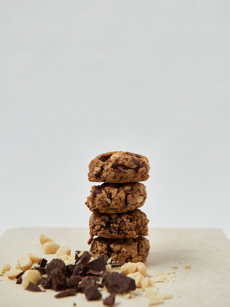 Macadamia Cookies gestapelt auf hellem Untergrund – frontale Aufnahme