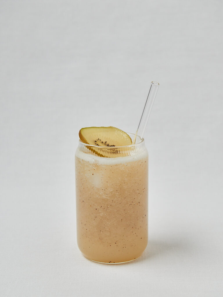 Kiwi Cooler mit Kiwischeibe und Strohhalm in einzelnem Glas – seitliche Studioaufnahme