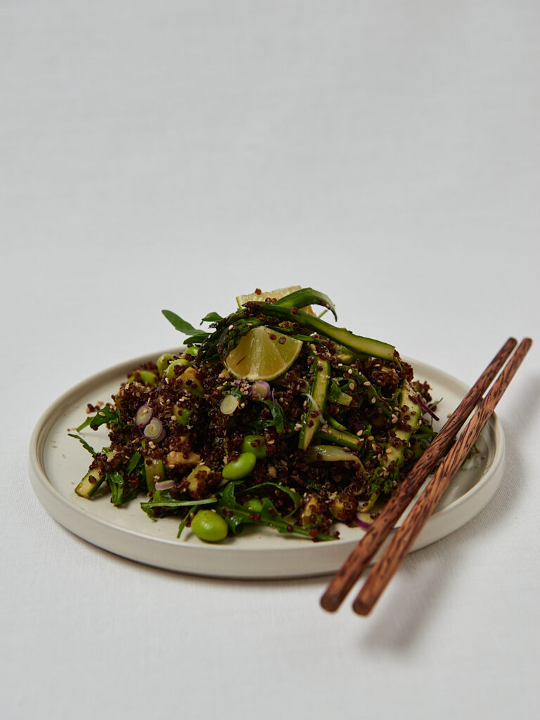 Crispy Roasted Quinoa Spargel Salat mit Edamame und Sesam in wei&szlig;er Sch&uuml;ssel mit St&auml;bchen &ndash; gesunder veganer Salat