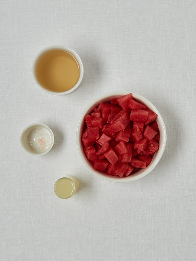 Zutaten-Flatlay Wassermelonen Cooler – Granatapfelkerne, Wassermelone und Honig