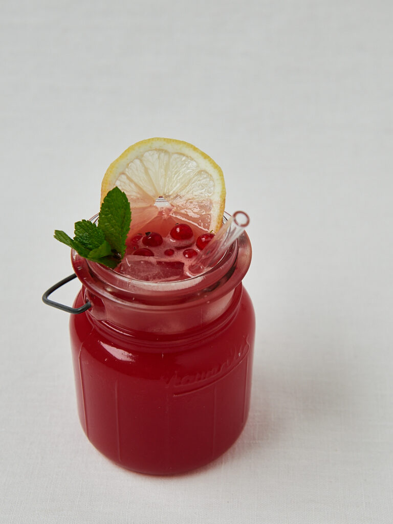 Wassermelonen Cooler in Glasschüssel mit Zitrone und Granatapfelkernen – seitliche Aufnahme