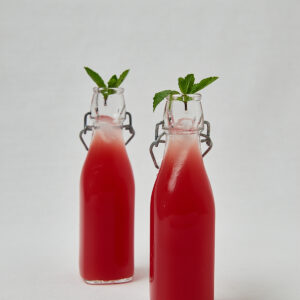 Roter Frucht Cooler in Glasflaschen mit frischer Minze – Overhead Shot