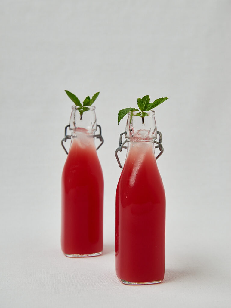 Roter Frucht Cooler in Glasflaschen mit frischer Minze – Overhead Shot
