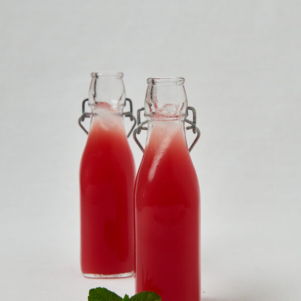 Wassermelonen Drink in B&uuml;gelflaschen auf hellem Untergrund &ndash; Studioaufnahme