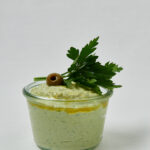 Green Olive Feta Dip mit Petersilie und Olive auf Teller – seitliche Nahaufnahme