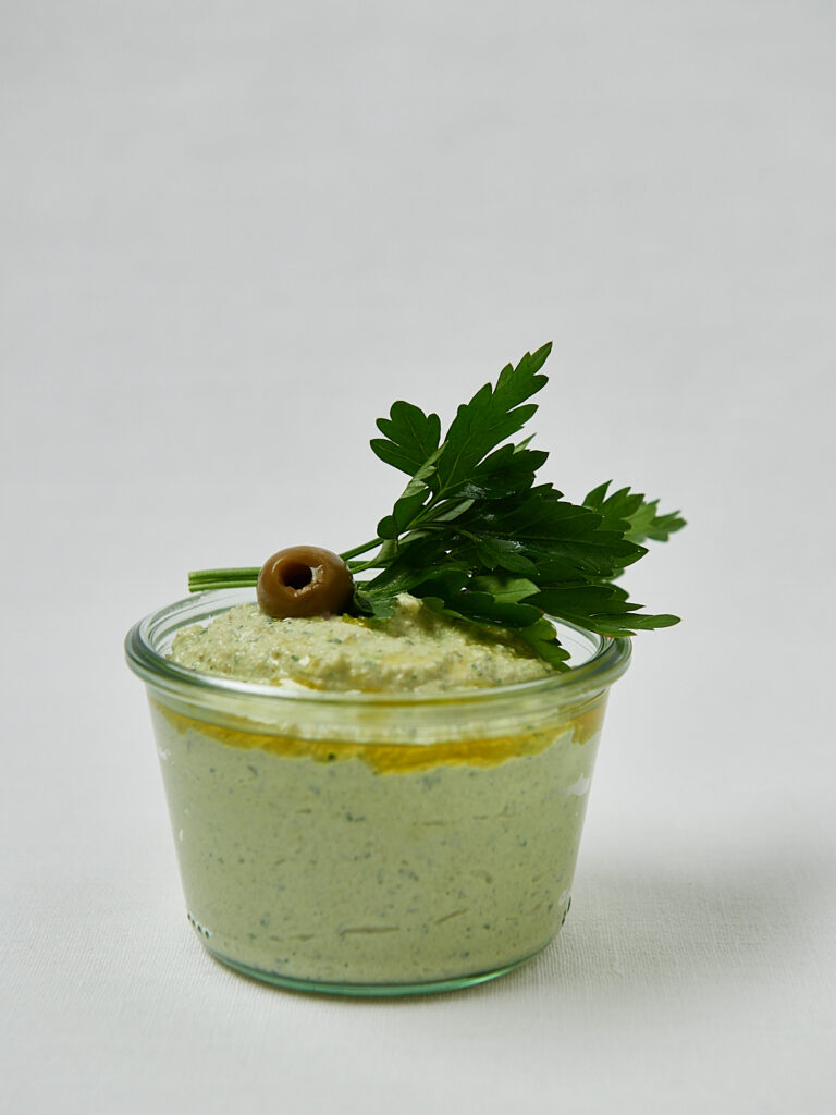 Green Olive Feta Dip mit Petersilie und Olive auf Teller – seitliche Nahaufnahme