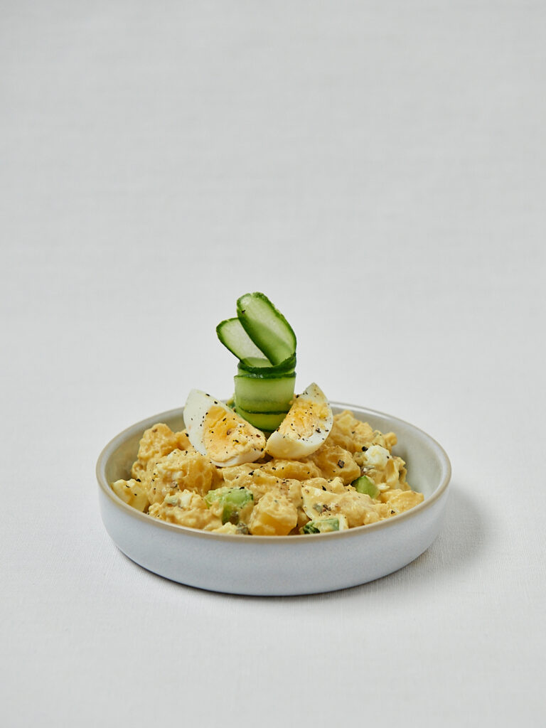 Kremiger japanischer Kartoffelsalat mit weichem Ei und Gurke – seitliche Studioaufnahme