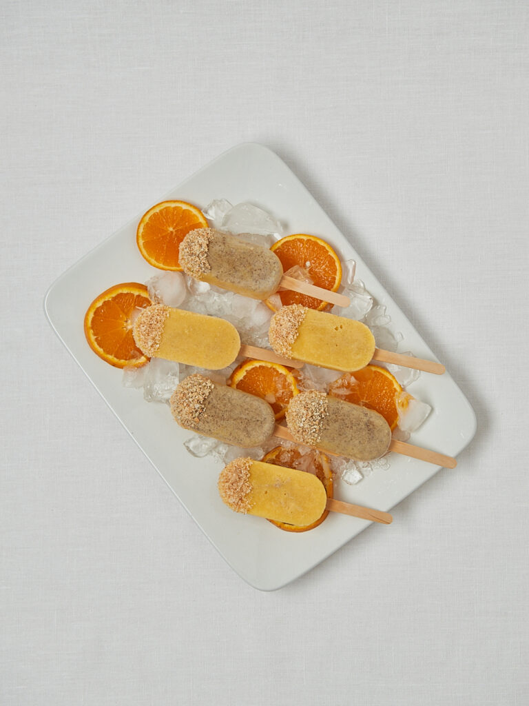 Mandarine Joghurt Popsicles auf Servierbrett – Overhead Shot mit Orangen