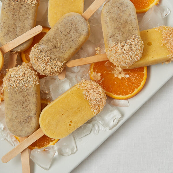 Gesunde Mandarine Joghurt Popsicles auf weißem Tablett – frontale Aufnahme