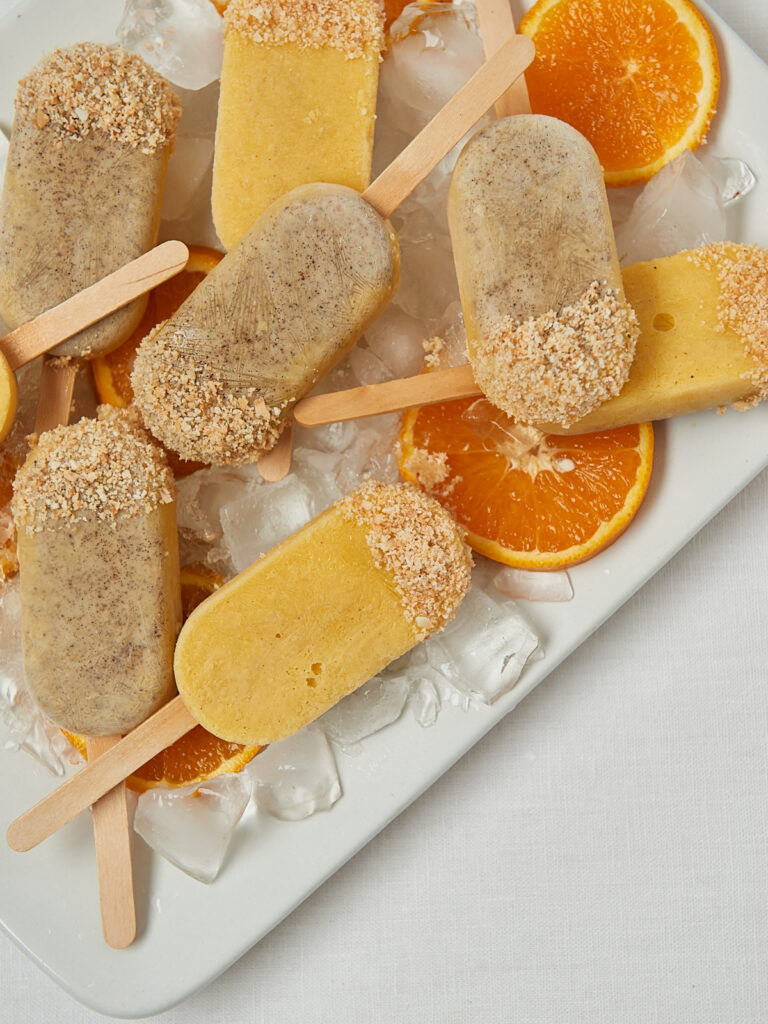 Gesunde Mandarine Joghurt Popsicles auf weißem Tablett – frontale Aufnahme