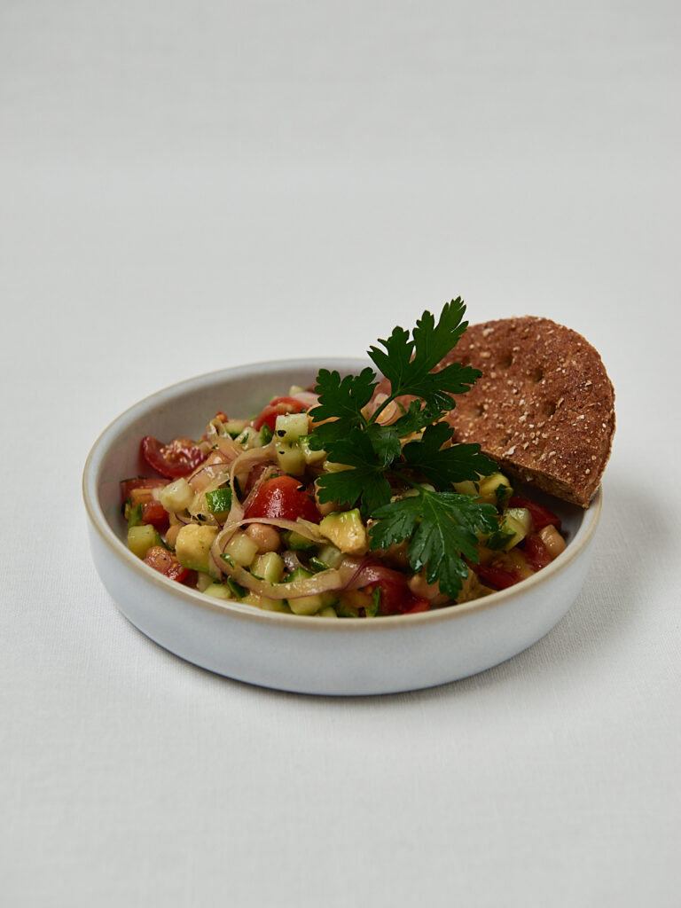 Gesunder Kichererbsen-Salat mit Gem&uuml;se und Vollkorncracker auf wei&szlig;em Teller