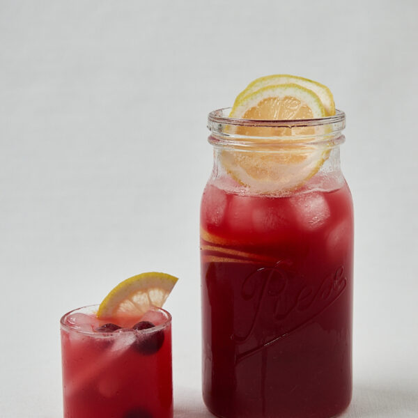 Hibiskus Kirsch Lemonade in Glasflasche mit Zitrone – seitliche Studioaufnahme