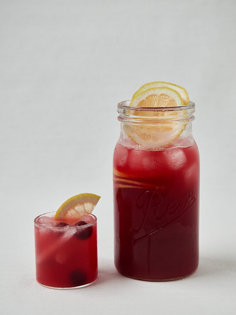 Hibiskus Kirsch Lemonade in Glasflasche mit Zitrone &ndash; seitliche Studioaufnahme