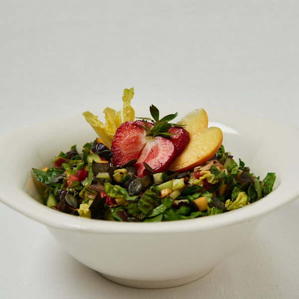 Skin Glow Salad mit Quinoa und frischen Früchten in weißer Schüssel – seitliche Aufnahme