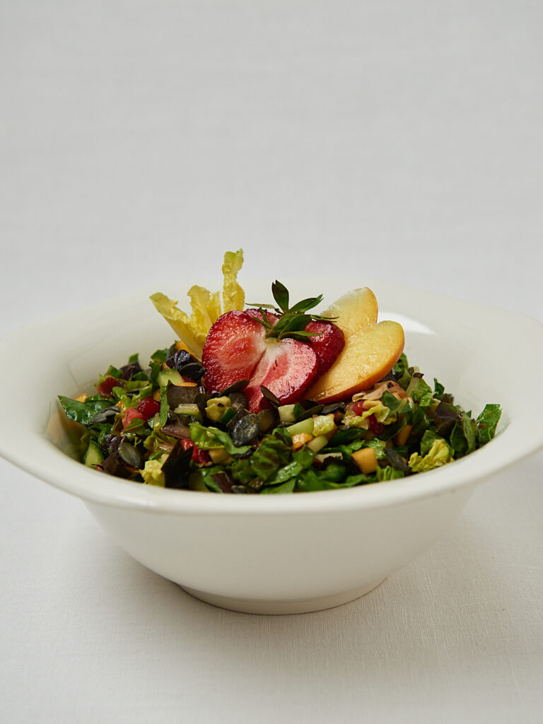 Skin Glow Salad mit Quinoa und frischen Fr&uuml;chten in wei&szlig;er Sch&uuml;ssel &ndash; seitliche Aufnahme
