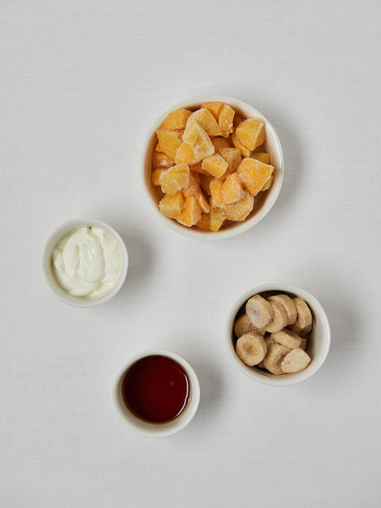 Zutaten-Flatlay Pfirsich Nice Cream – Pfirsichstücke, Joghurt und Honig in Schälchen
