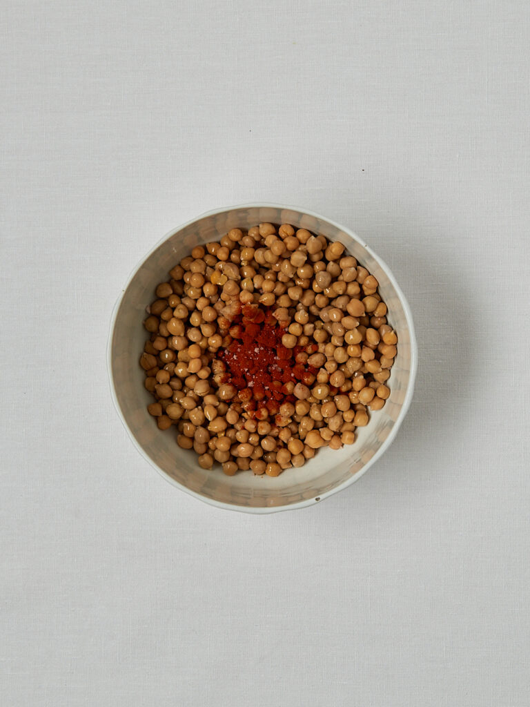 Rohe Kichererbsen mit Paprika in Schüssel – Zubereitungsschritt vor dem Rösten
