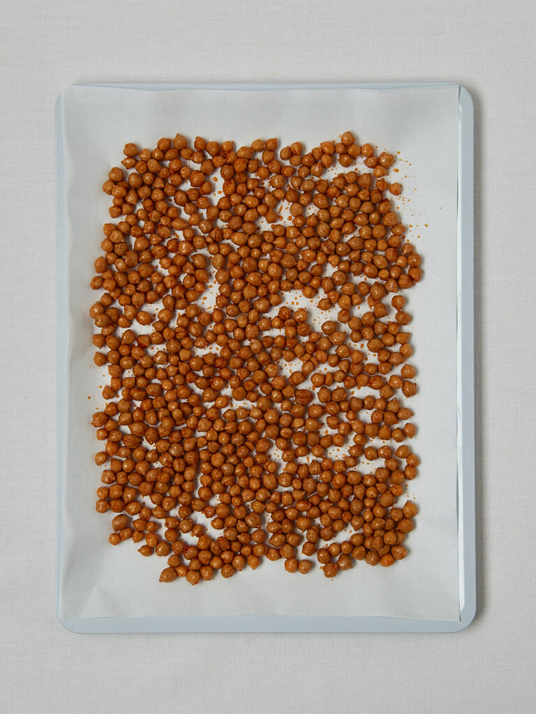 Cheezy Chickpeas auf Backblech gleichmäßig verteilt – Zubereitungsschritt Overhead