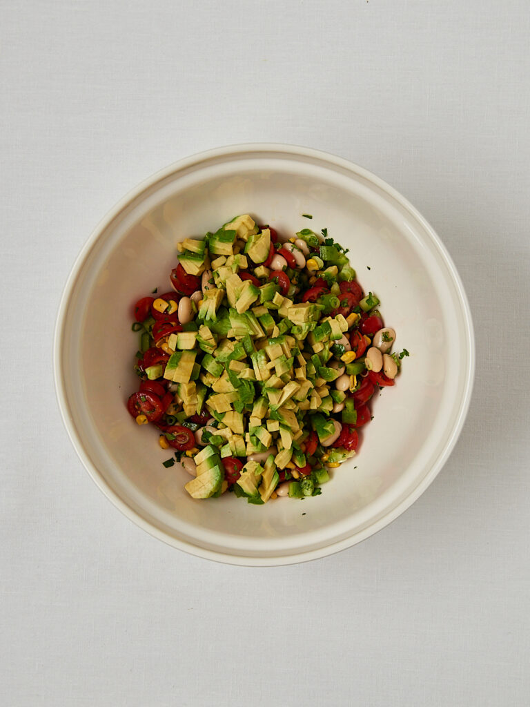 Bohnensalat mit Kirschtomaten und Edamame in Sch&uuml;ssel &ndash; Overhead Shot Wei&szlig;e Bohnen, Mais und Kirschtomaten in Sch&uuml;ssel vor dem Vermengen &ndash; Zubereitungsschritt