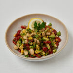 Butter Bean Corn Salad mit Kräutern und Zitronenscheibe – frontale Studioaufnahme
