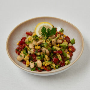 Butter Bean Corn Salad mit Kr&auml;utern und Zitronenscheibe &ndash; frontale Studioaufnahme