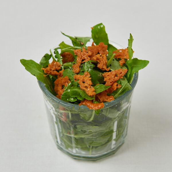 Knusprige Käse Croutons mit frischem Rucola in Glasschüssel – frontale Aufnahme