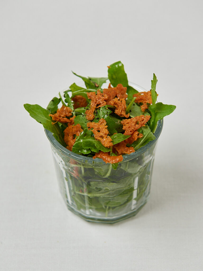 Knusprige K&auml;se Croutons mit frischem Rucola in Glassch&uuml;ssel &ndash; frontale Aufnahme