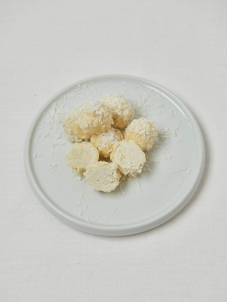 Gesunde Raffaello Balls auf wei&szlig;em Teller &ndash; seitliche Nahaufnahme