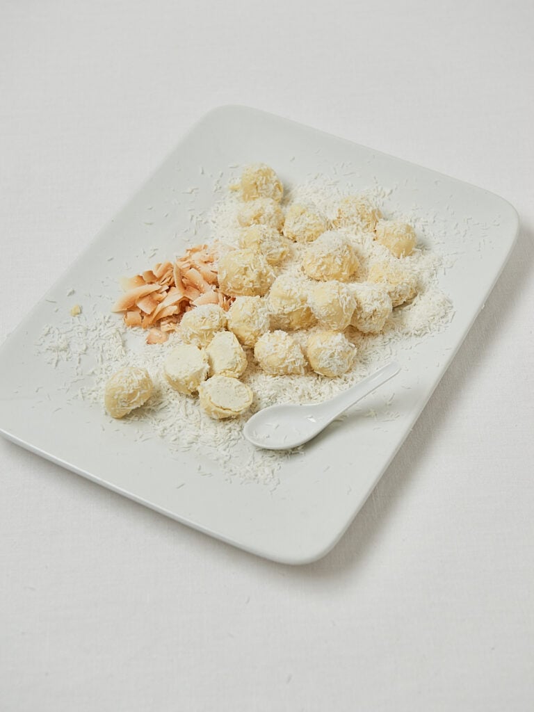 Kokos Energy Balls auf wei&szlig;em Teller &ndash; frontale Studioaufnahme