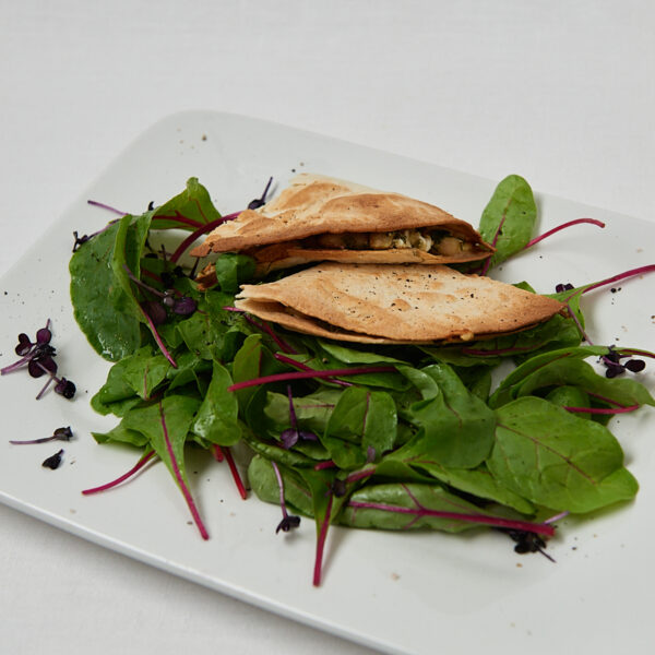 Bean Pesto Wrap mit Salat auf wei&szlig;em Teller &ndash; Draufsicht Studioaufnahme