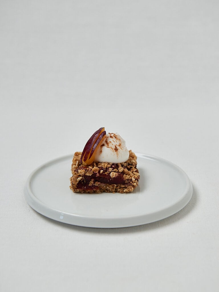 Pflaumen Crumble Riegel mit Topping auf wei&szlig;em Teller &ndash; Overhead Shot
