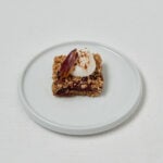 Pflaumen Crumble Bar mit cremigem Topping auf Teller – frontale Studioaufnahme