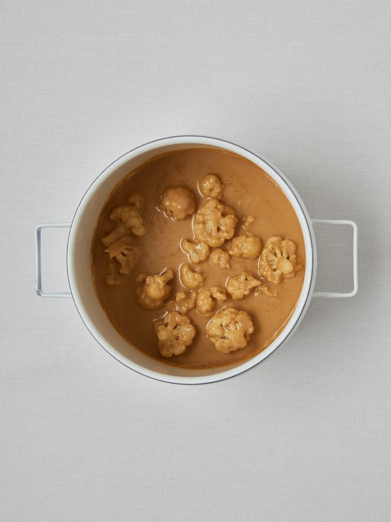 Blumenkohl in Sauce in weißem Topf – Zubereitungsschritt Creamy Cauliflower